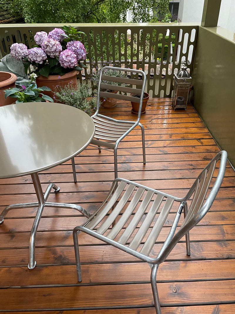 Runder Bättig Gartentisch und Bättig Gartenstühle in der Farbe Schlamm auf einem verregneten Balkon