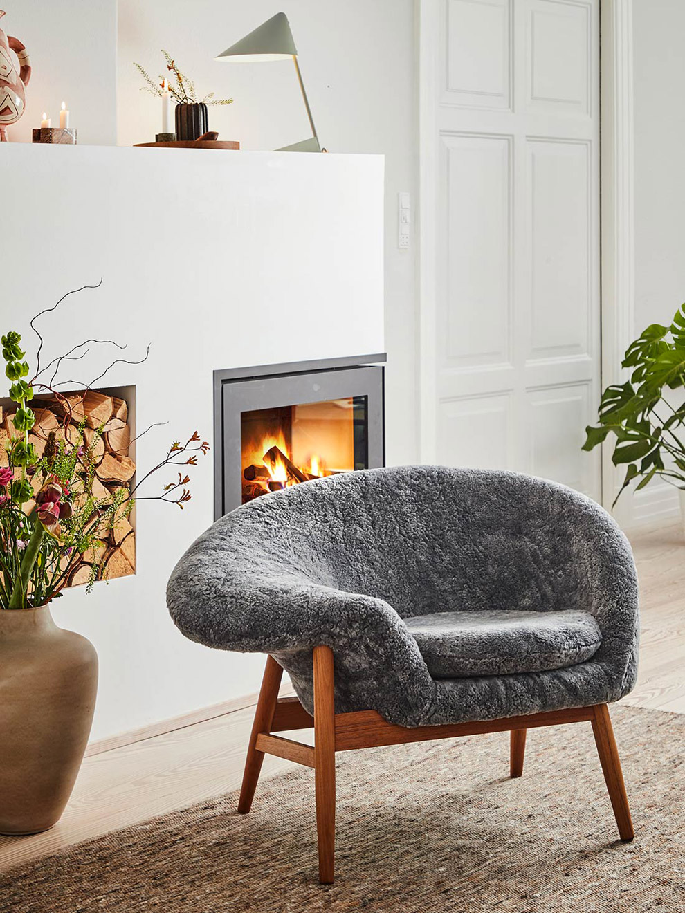 Fried Egg Lounge Chair mit Schaffell in grau vor einem Cheminée