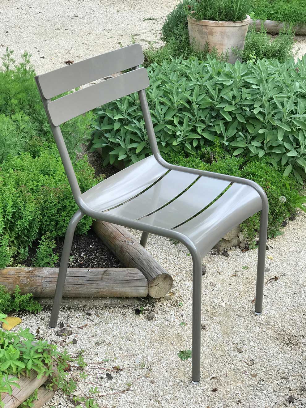 Luxembourg Gartenstuhl in der Farbe «Schlamm» in einem Garten mit Kräutern