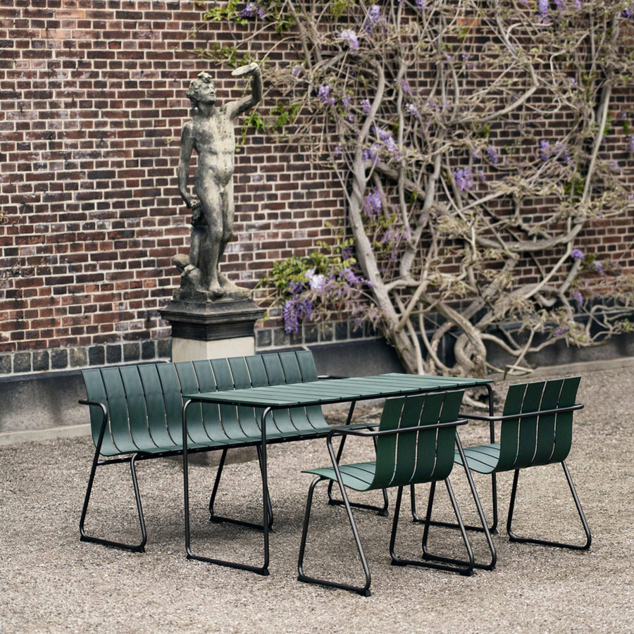 Ocean Gartenstühle, Gartentisch und Gartensitzbank in Grün auf Kiesuntergrund mit blühender Glyzinie im Hintergrund
