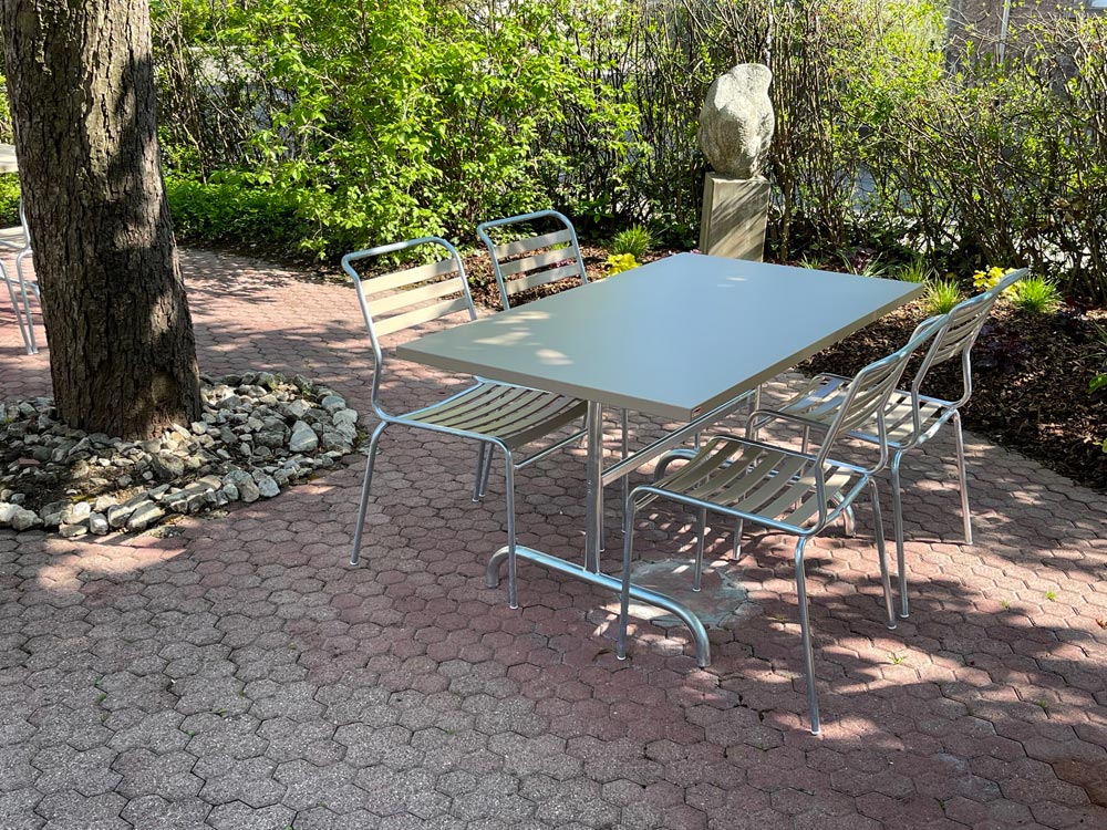 Gartentisch und Gartenstühle des Modells «Säntis» von Schaffner in einem Garten in der Frühlingssonne.
